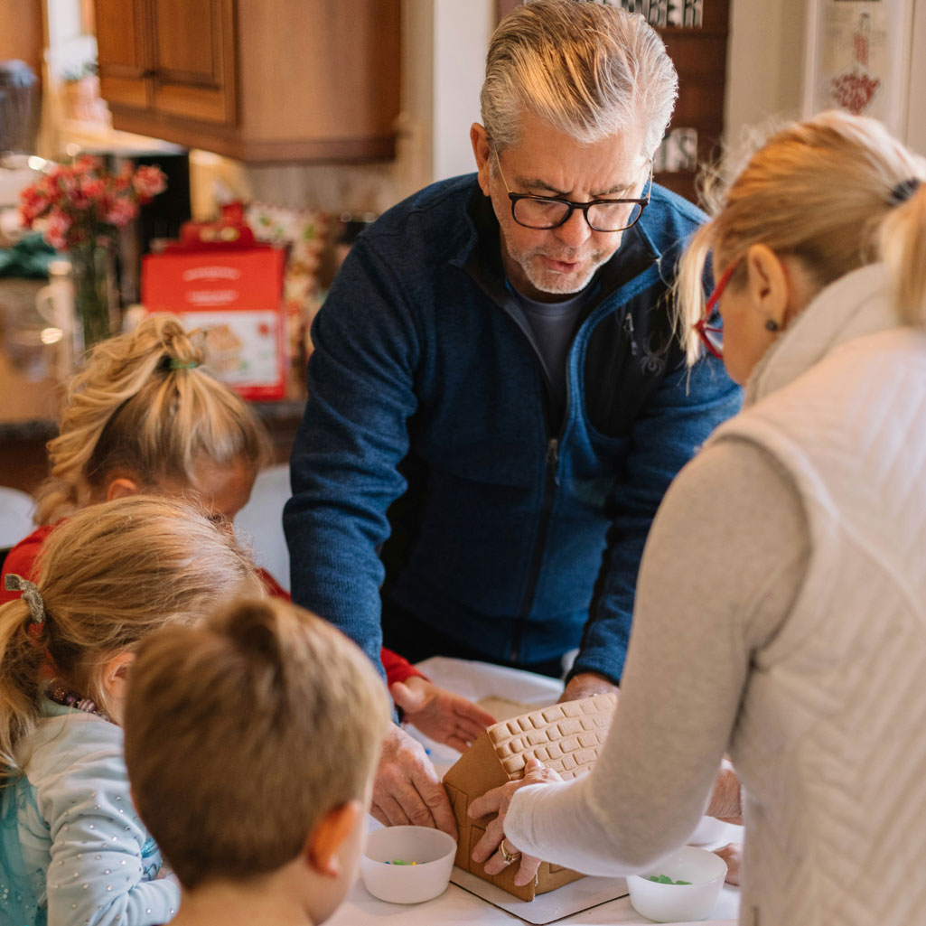 Grandparents building gingerbread with their grandchildren