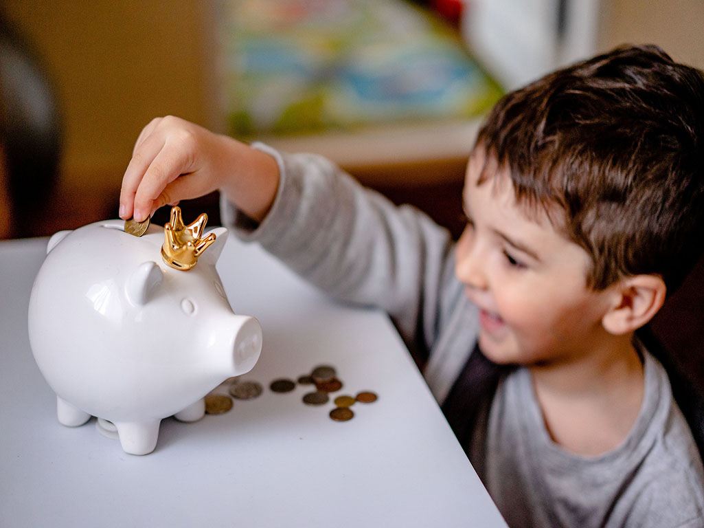 Child putting coins in piggy bank